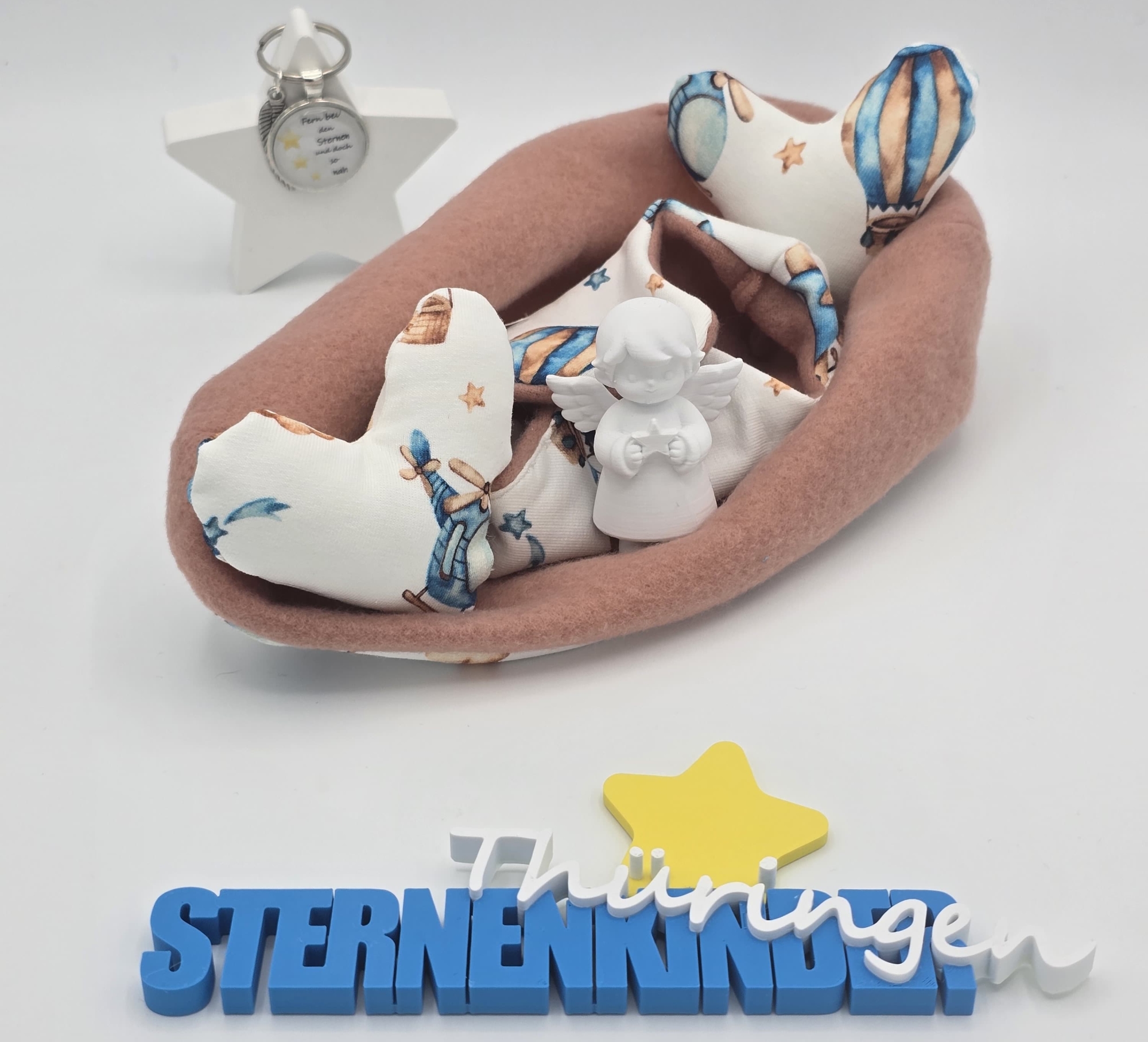 Rosafarbene Einschlagdecke mit hellem Stoff mit Sternen- und Wolkenmotiven und kleiner Engelfigur