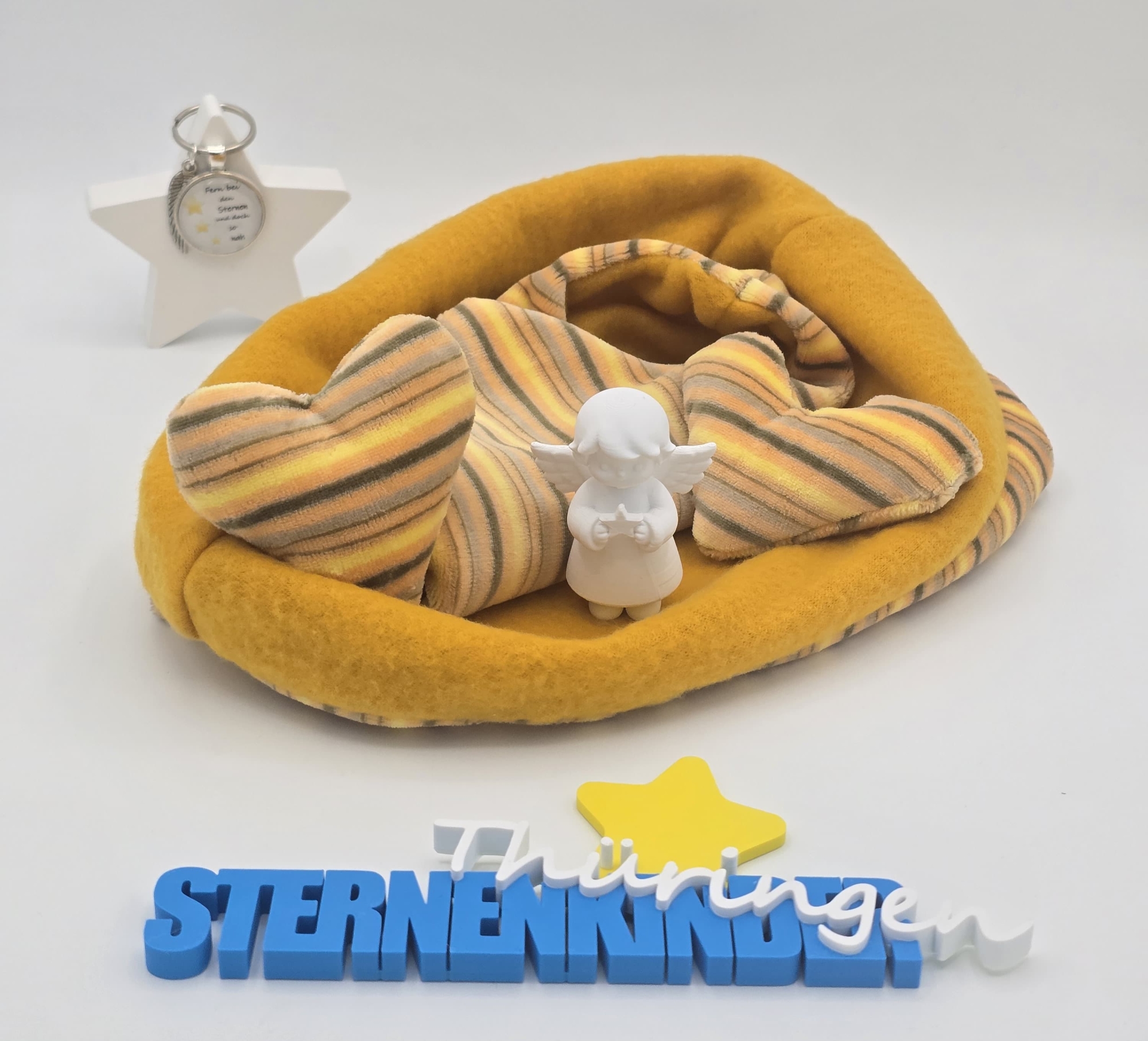 Goldgelbe Einschlagdecke mit gestreiften Stoffherzen und kleiner Engelfigur